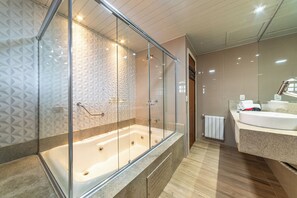 Un baño moderno con ducha envuelta en vidrio, bañera blanca y tocador con espejo.