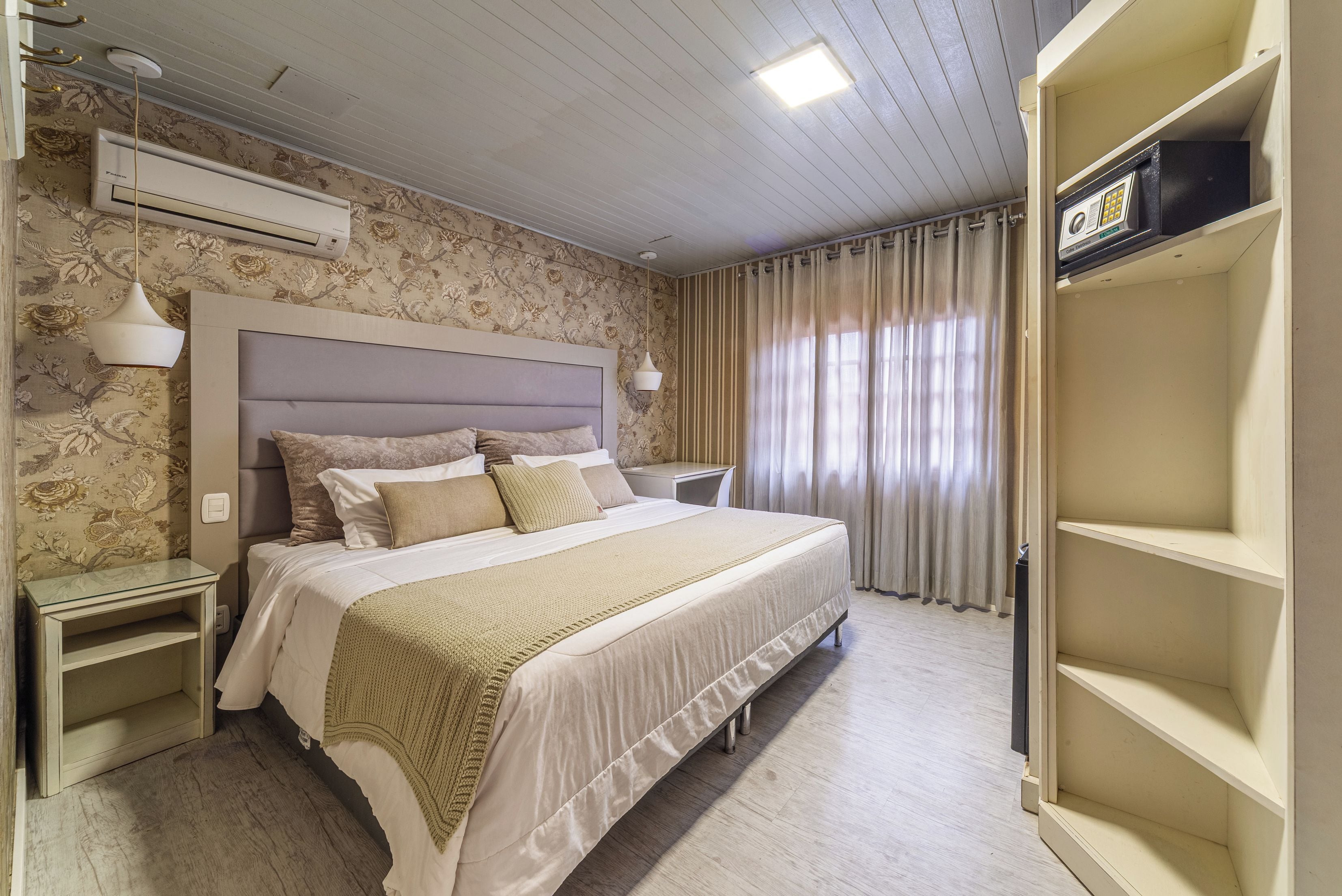 Habitación de hotel con una cama grande, mesitas de noche, un armario y un ventilador de techo.