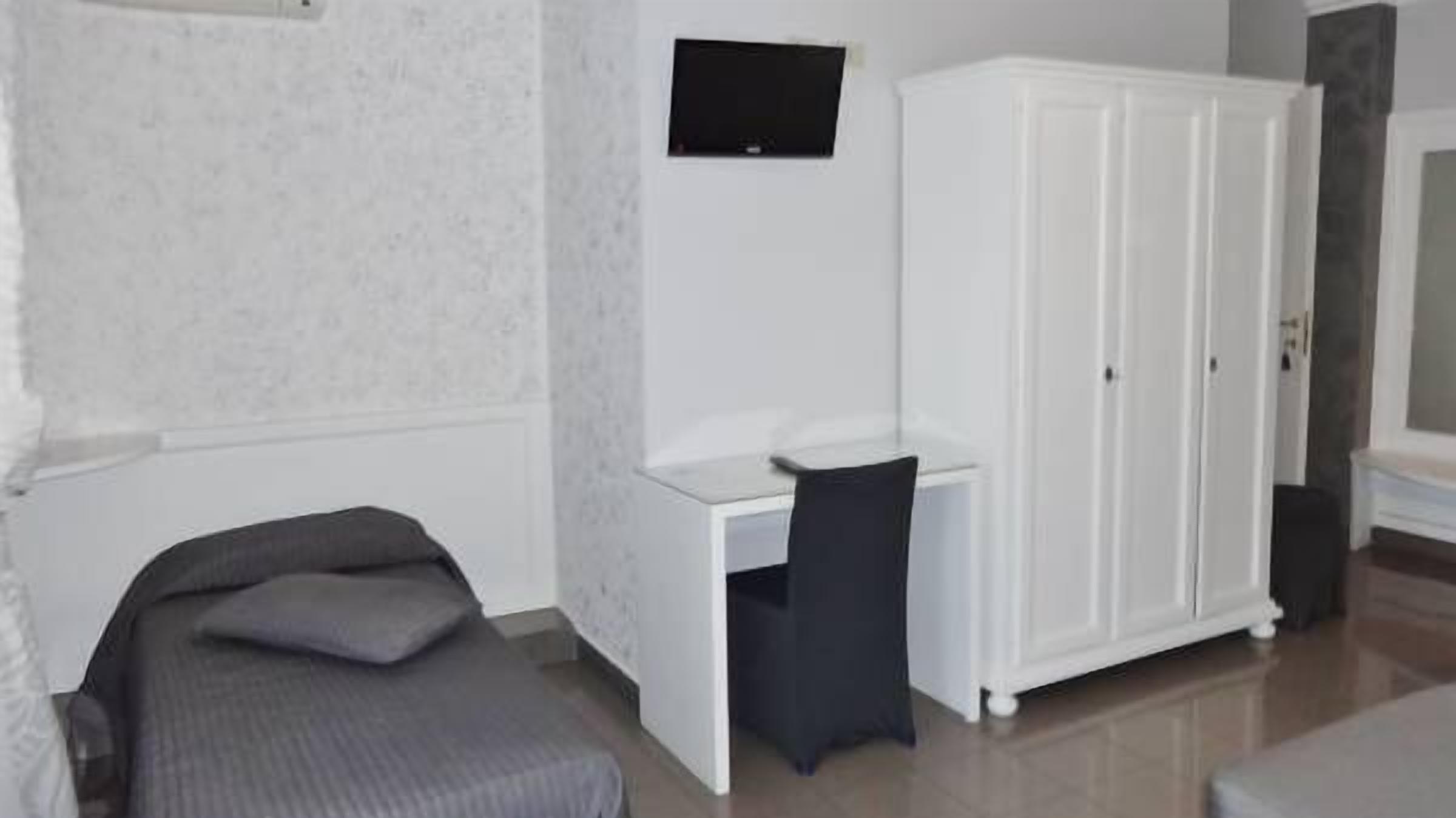 A room with a bed, a desk, and a wardrobe.
