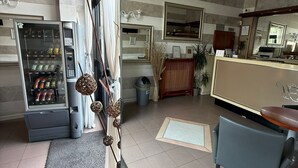 A hotel lobby with a vending machine, a reception desk, a chandelier, and a mirror. - Hotel Marte (Milan)