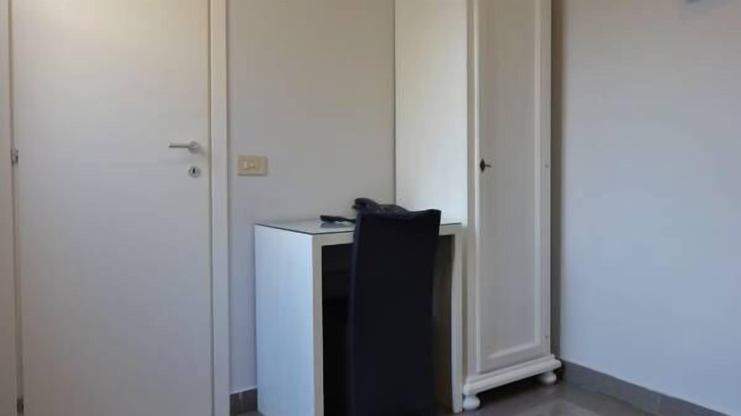 A room with a desk, chair, and wardrobe.