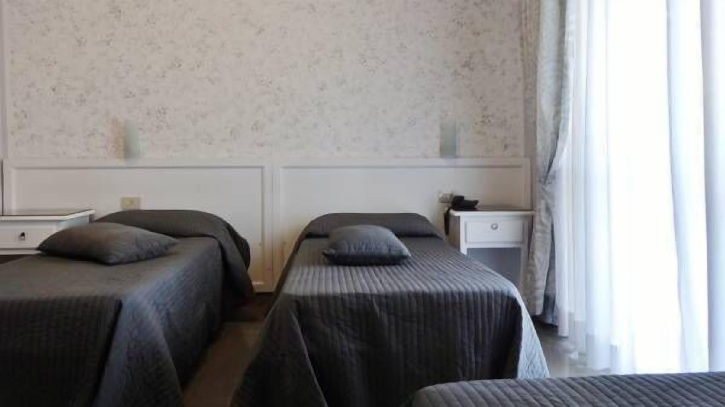 Hotellihuone, jossa on kaksi erillistä sänkyä, ja jokaisessa sängyssä on tyyny ja yöpöytä.