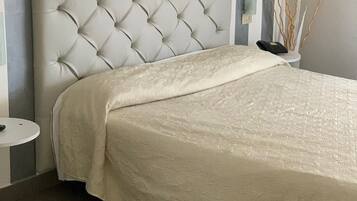 Una camera da letto con una testiera trapuntata, un letto con copriletto texturizzato, un comodino e una parete a righe verticali.