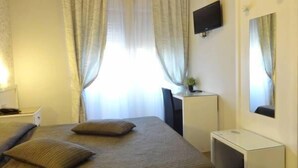 A hotel room with a bed, a desk, a TV, and a mirror. - Hotel Marte (Milan)