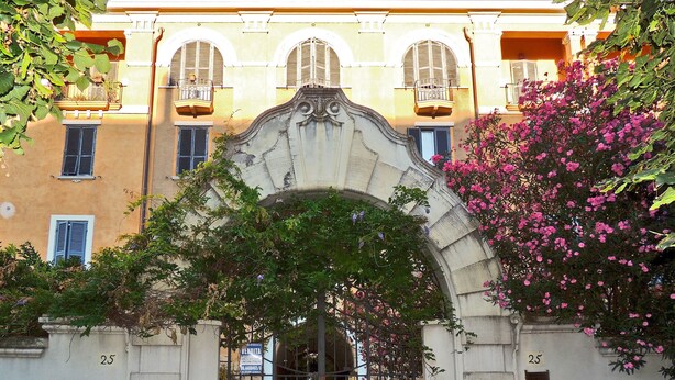 Un edificio con un arco ornamentado, número 25, y un letrero que indica rebajas.