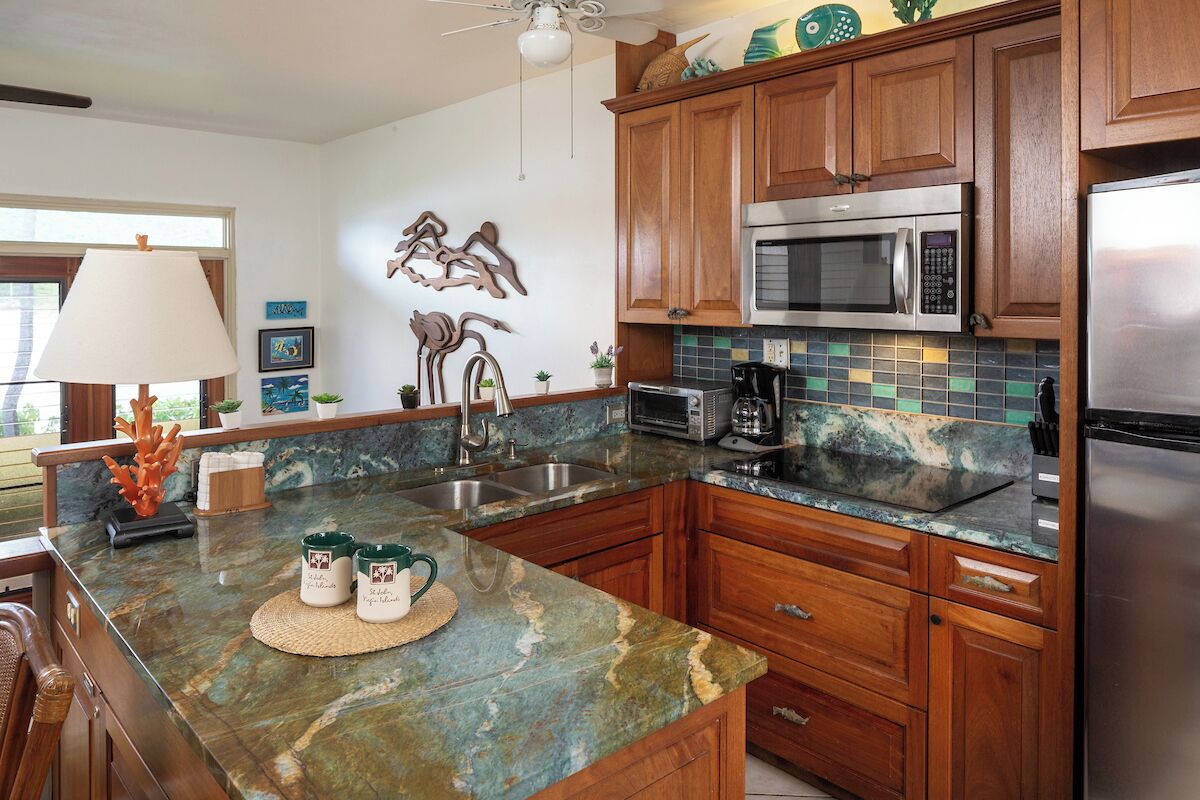A modern kitchen with wooden cabinets, a stainless steel refrigerator, a microwave, and a coffee maker.