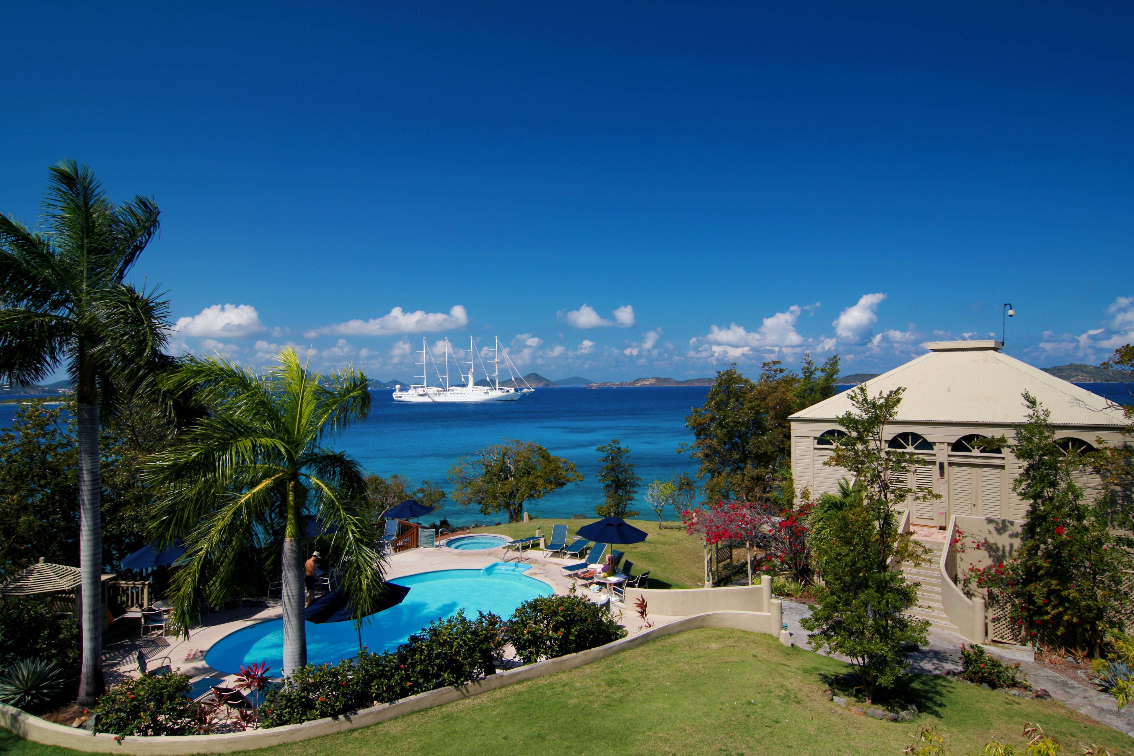 Un resort con una amplia piscina, palmeras y vista al océano.