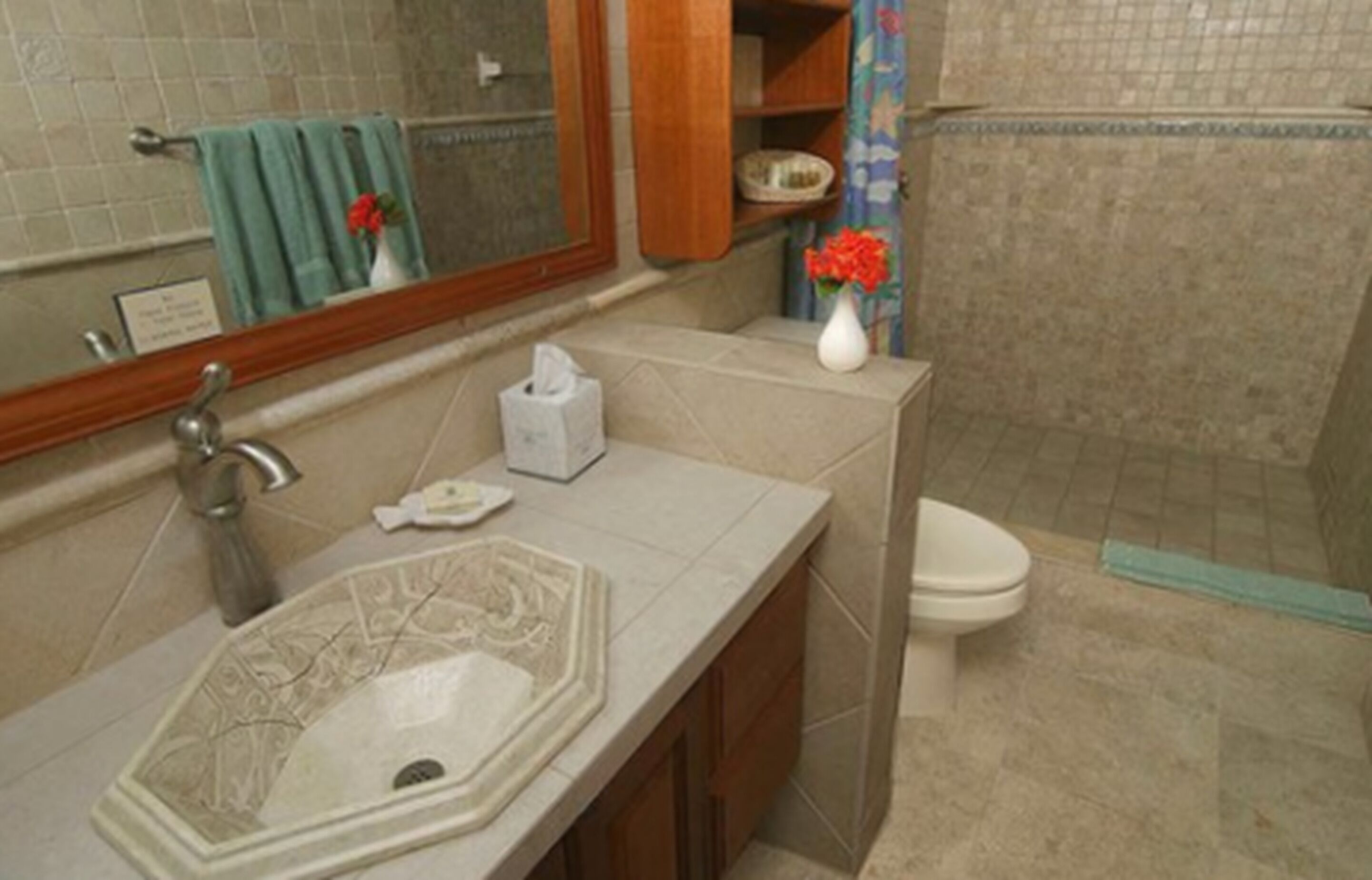 A bathroom with a sink, mirror, toilet, and shower.