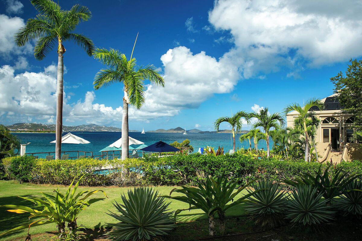 A resort with palm trees, a pool, and a view of the ocean.