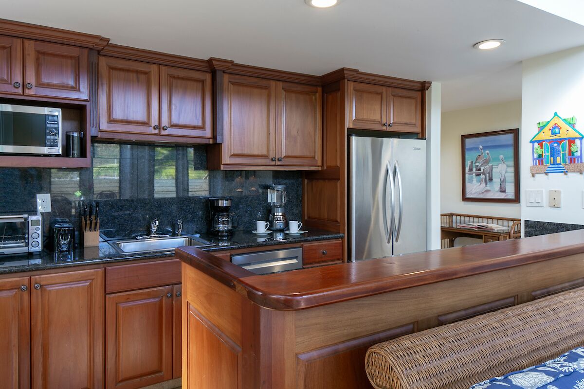 A kitchen with wooden cabinets, a stainless steel refrigerator, a microwave, and a coffee maker.