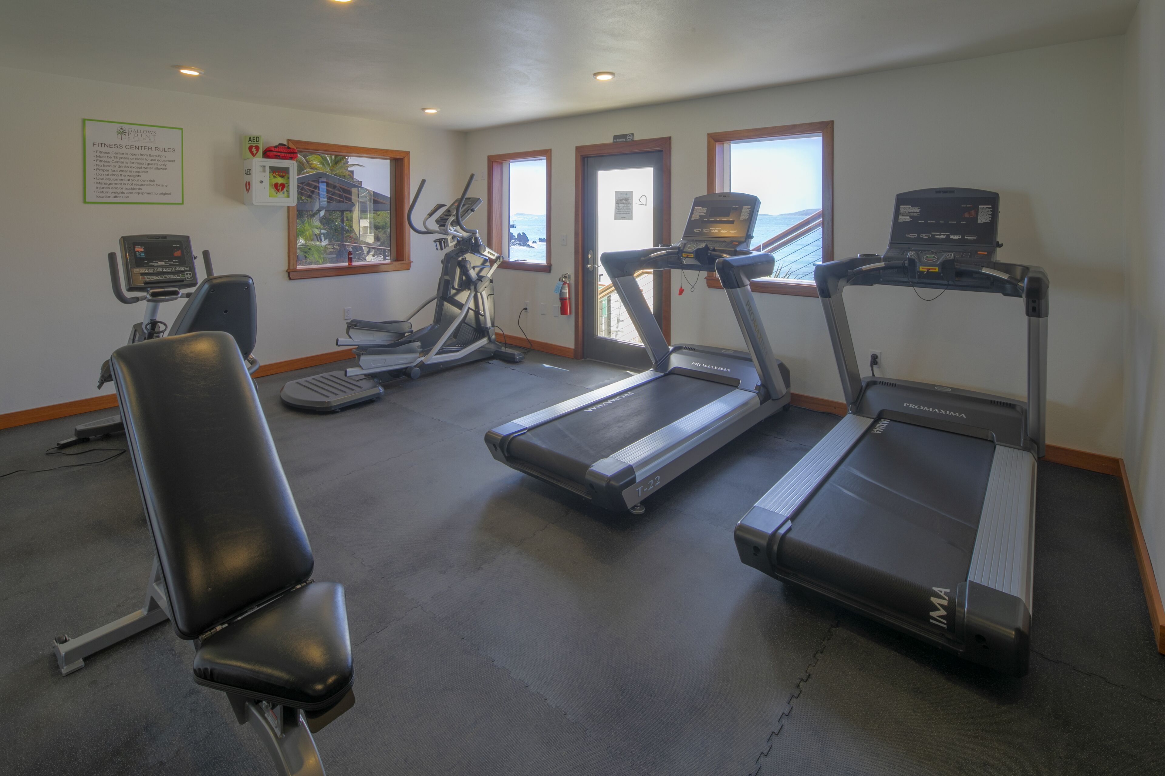 Un gimnasio con cintas de correr, una bicicleta estática y un banco para pesas.
