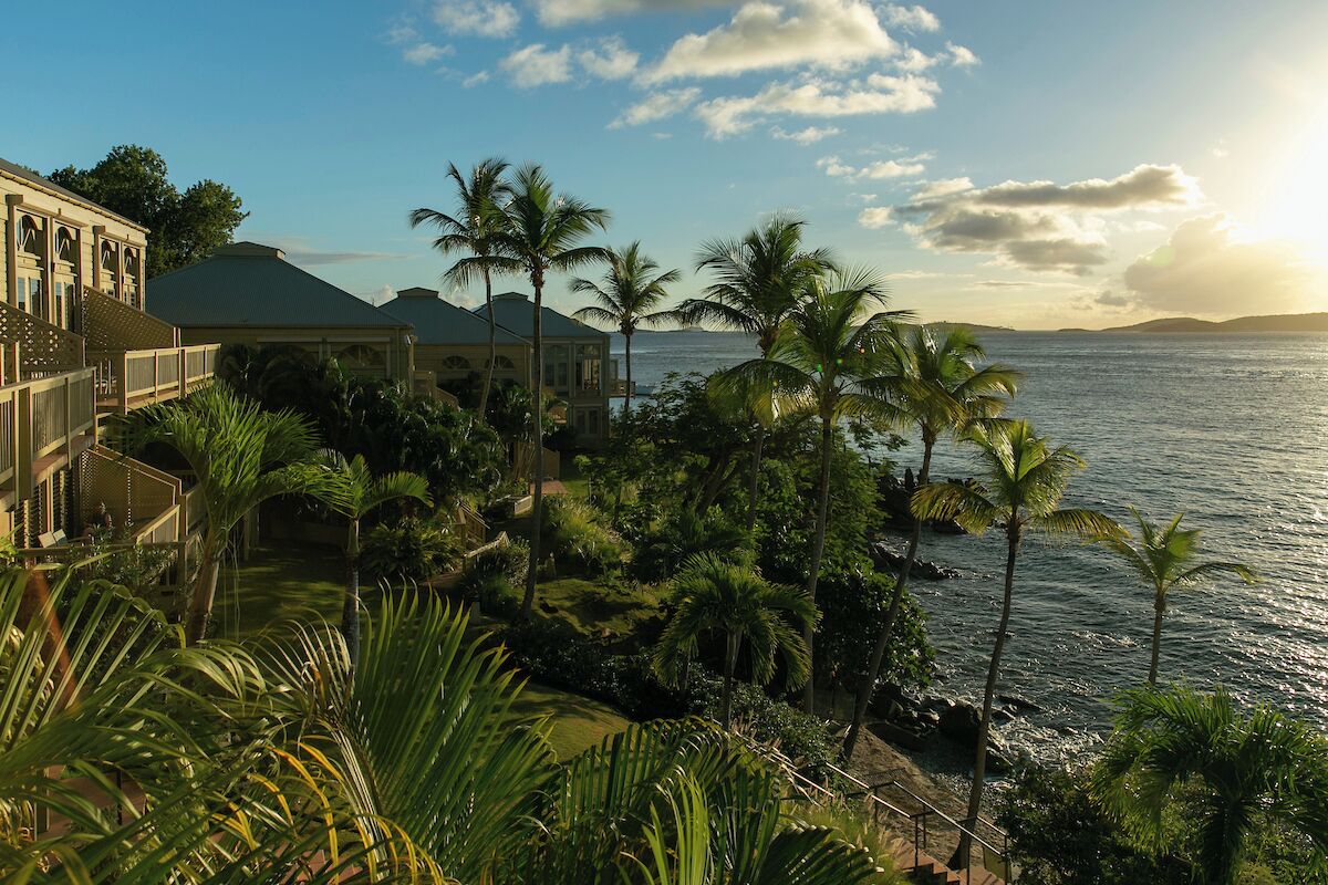A beachfront property with a large building, palm trees, and a view of the ocean.