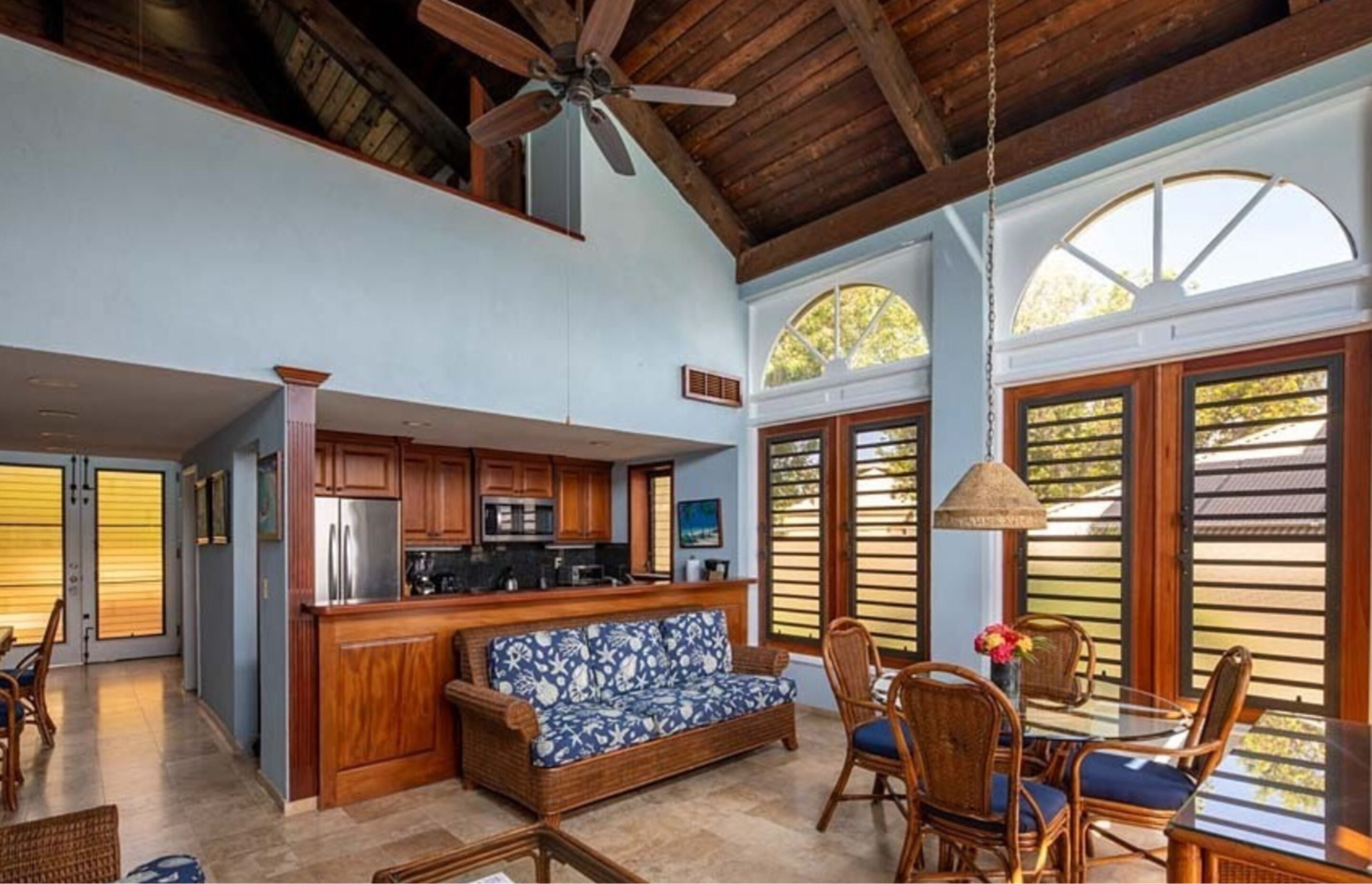 A spacious kitchen with wooden cabinets, a central island, and a dining area with wicker furniture.