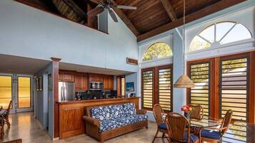A spacious kitchen with wooden cabinets, a central island, and a dining area with wicker furniture.