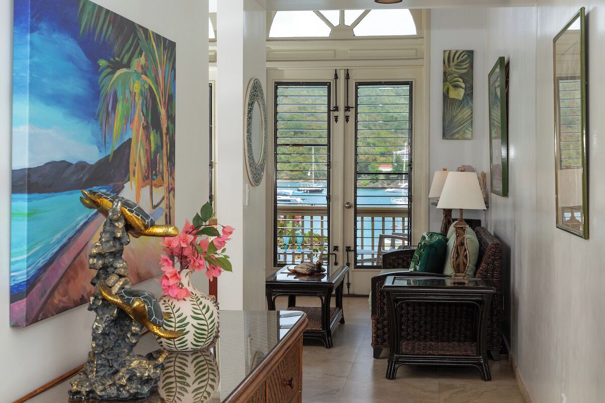 A room with a view of the sea, a painting of a tropical scene, and a decorative sculpture.
