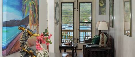 A room with a view of the sea, a painting of a tropical scene, and a decorative sculpture.