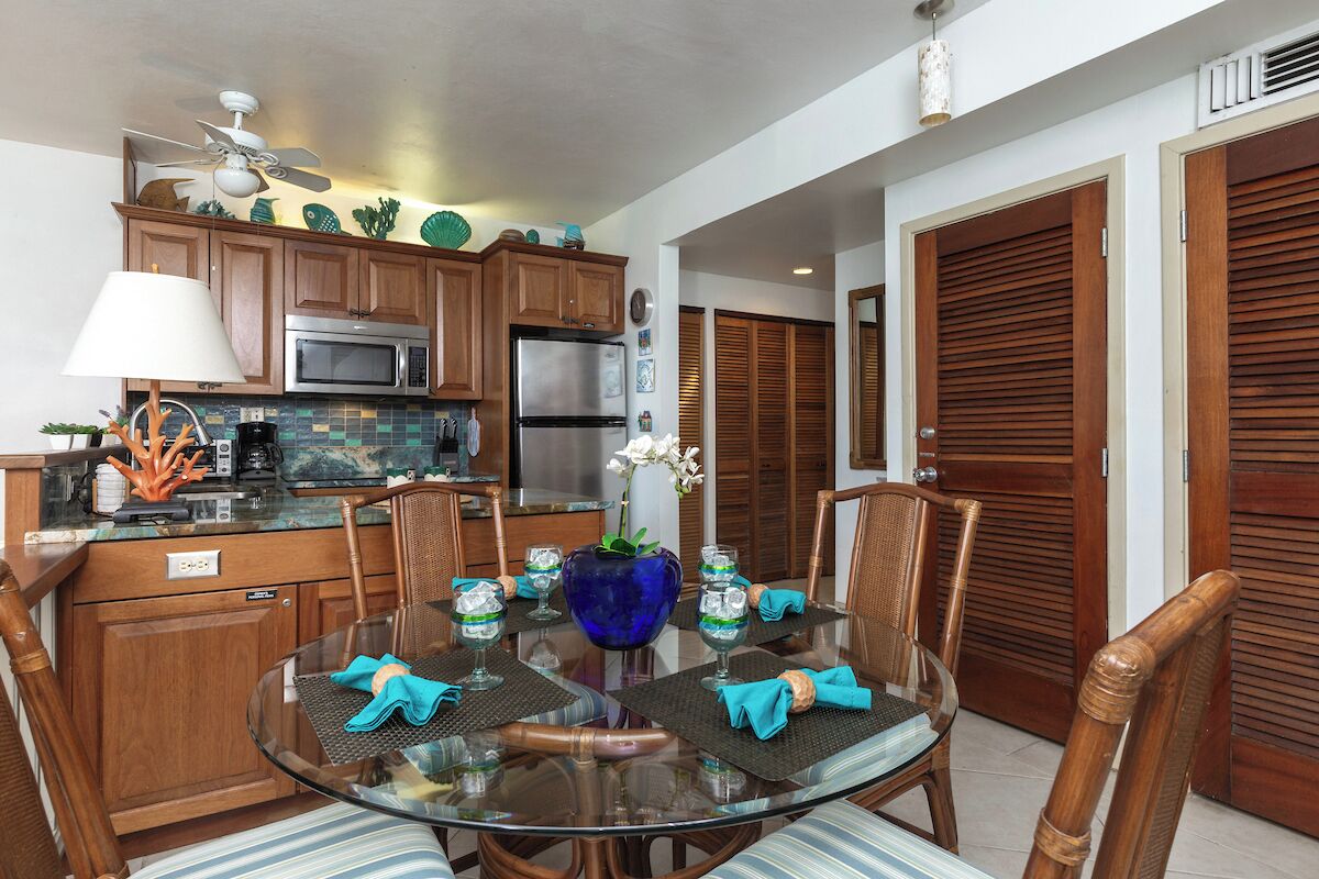 A modern kitchen with wooden cabinets, stainless steel appliances, and a dining area with a glass table and chairs.
