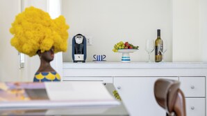 Una cocina con cafetera, frutero y botella de vino.