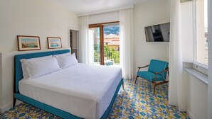 Habitación de hotel con cama, una silla, televisión y balcón con vistas.