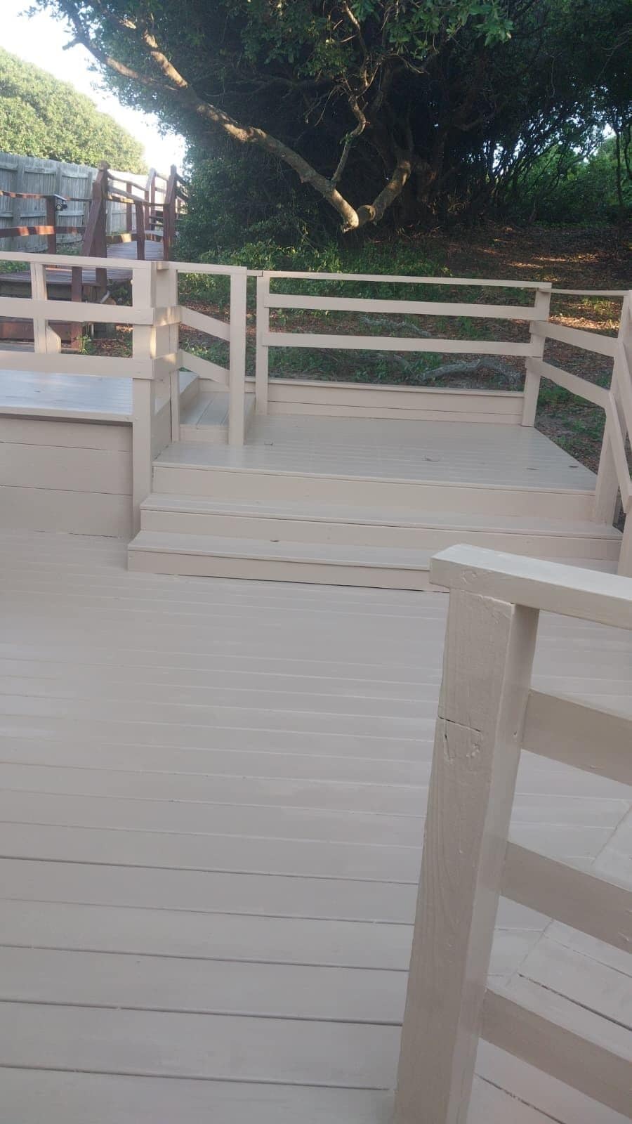 A wooden deck with steps leading to a seating area, surrounded by trees.