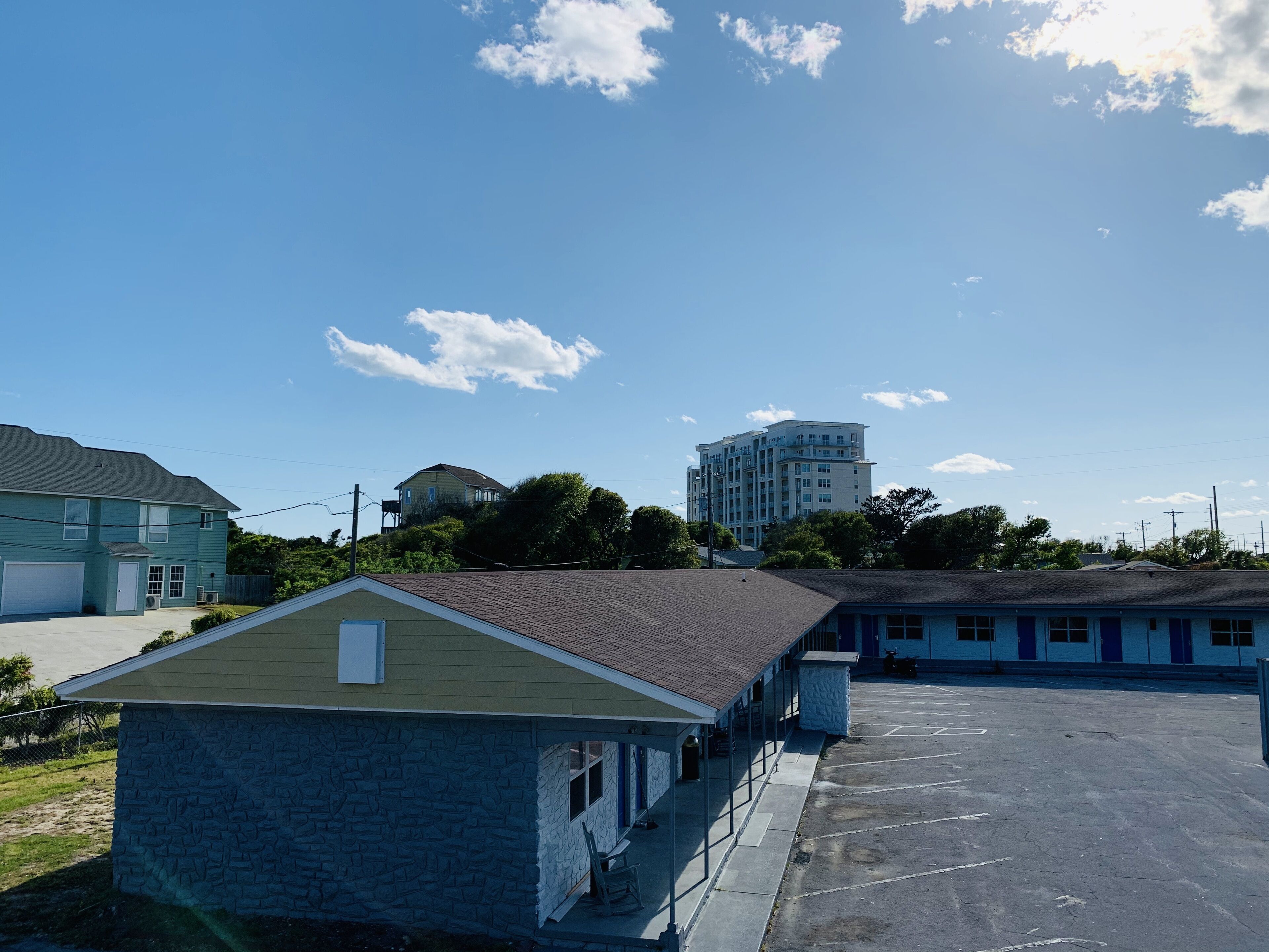 A parking lot with a building that has a stone facade and a flat roof.