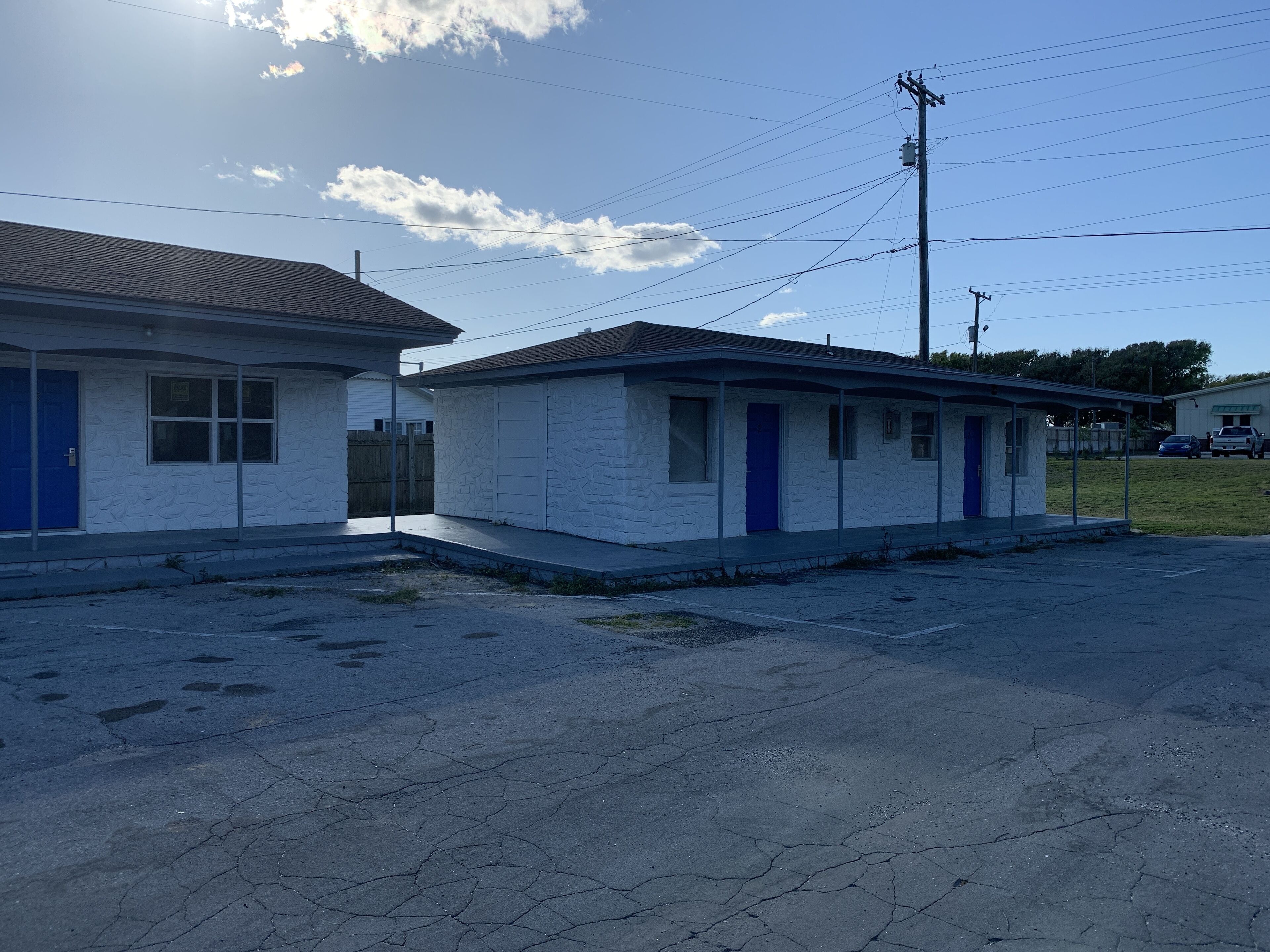 A two-story building with a flat roof, a blue door, and a small porch.