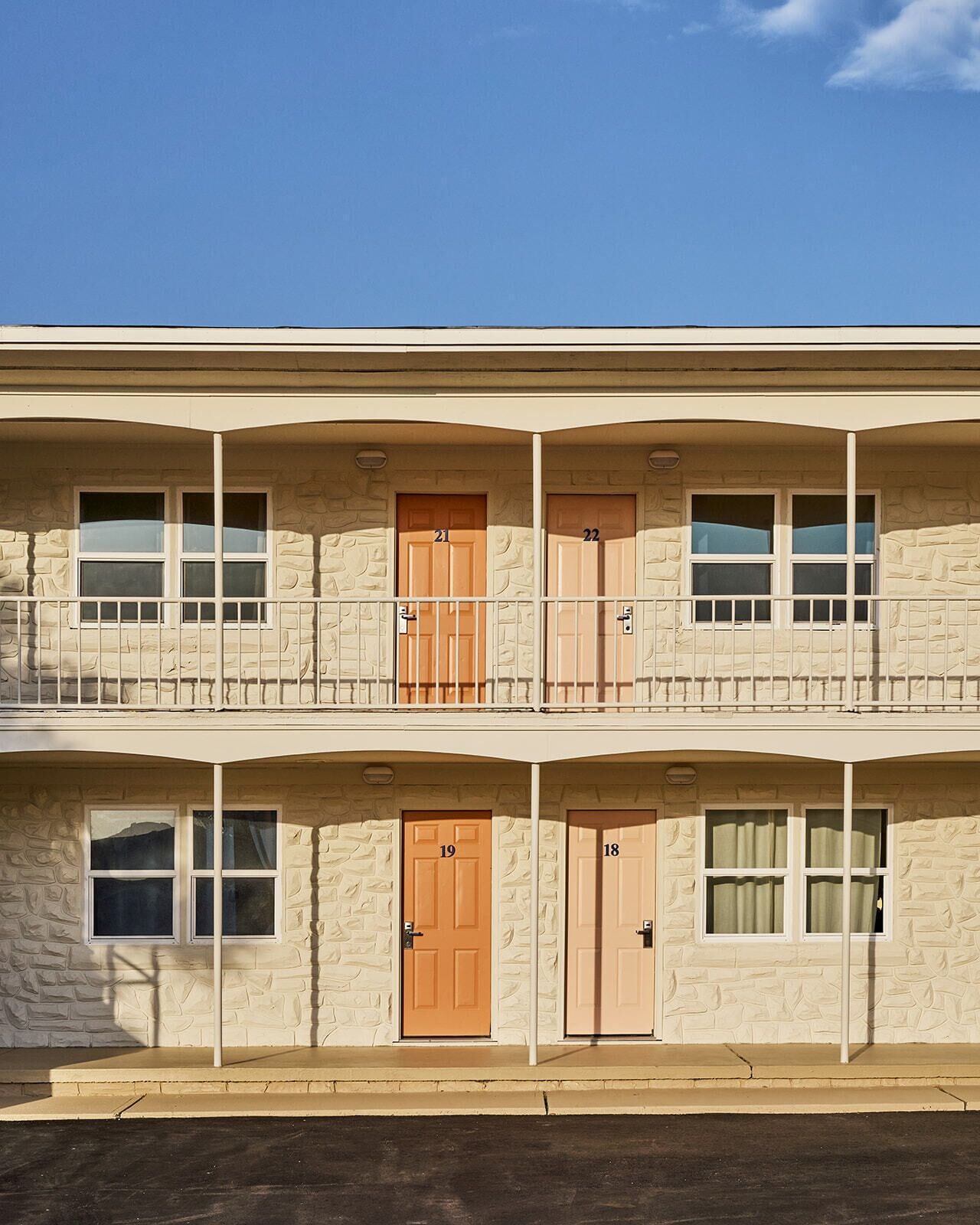 A two-story building with numbered doors, balconies, and windows.