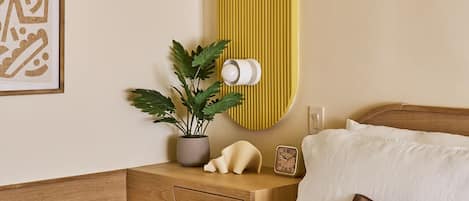 A neatly arranged hotel room with a bed, bedside table, and a wall-mounted lamp.