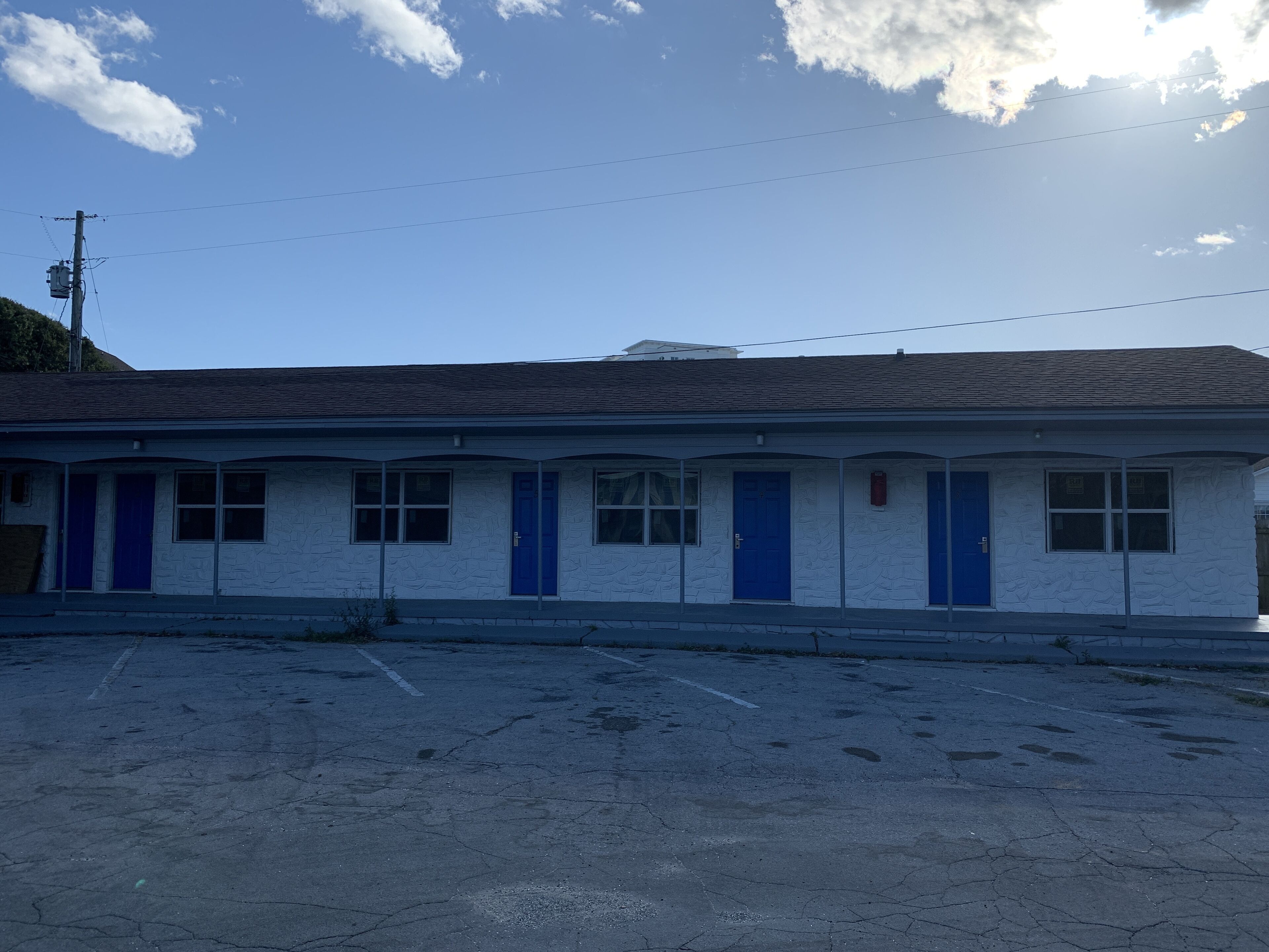 A motel with a row of rooms, each with a blue door and windows.