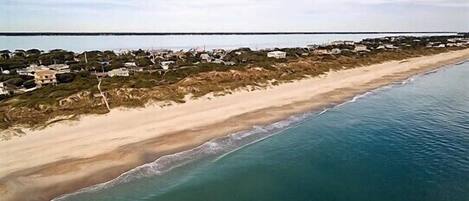 An aerial view of a beach with houses along the shoreline.