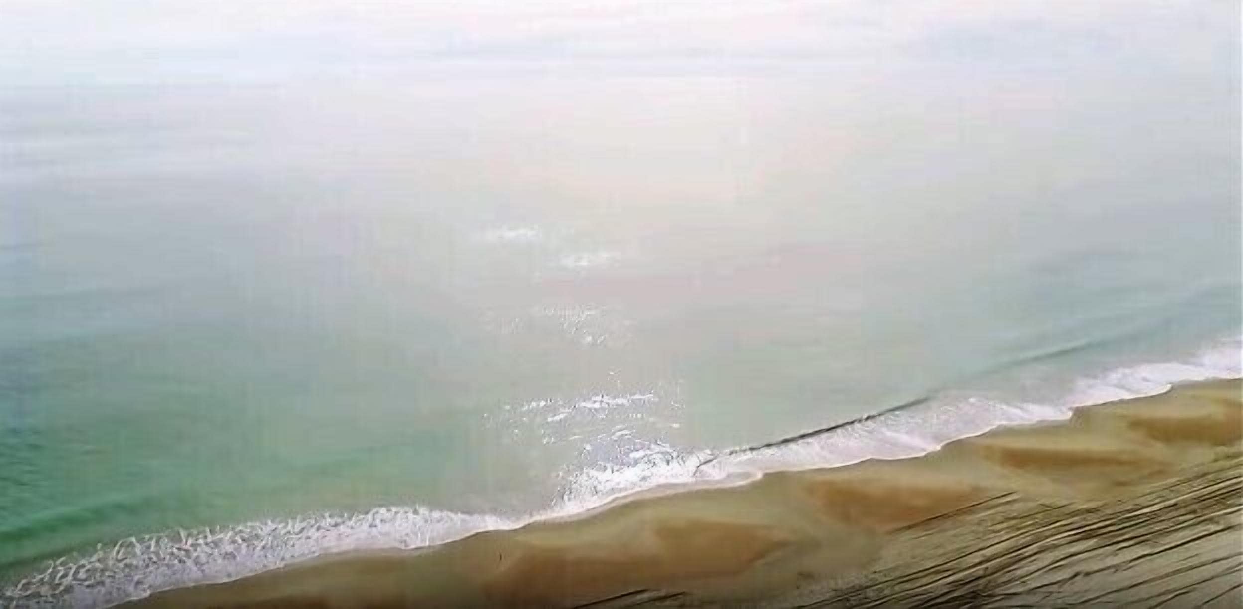 A beach with a sandy shore and gentle waves.
