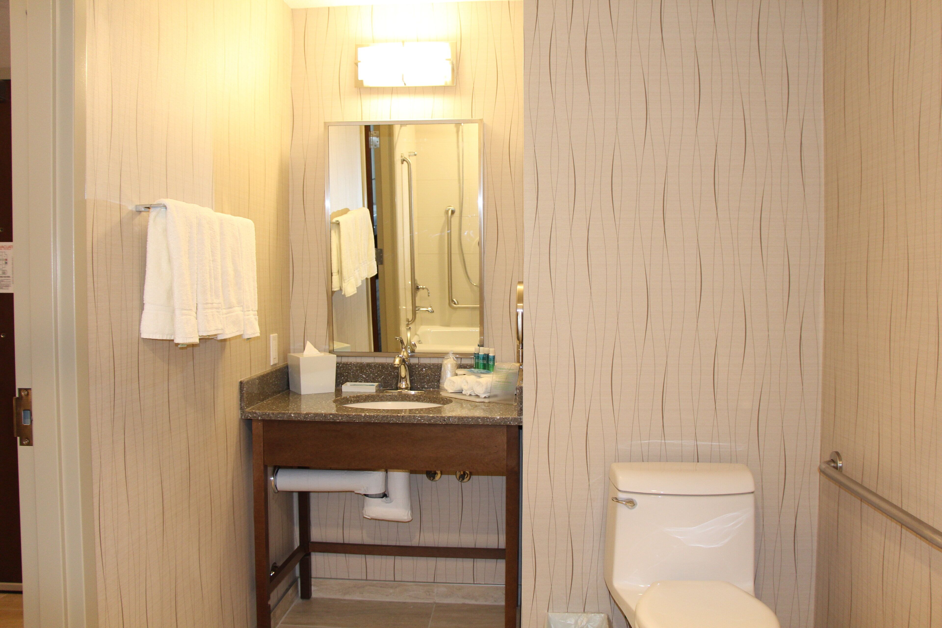Ein Badezimmer mit Waschbecken, Spiegel, Handtuchhalter, Toilette und Dusche.