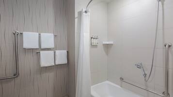 A bathroom with a shower, a bathtub, and handrails.