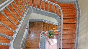 Una escalera de madera con barandilla metálica, un arreglo floral y una caja de regalo.