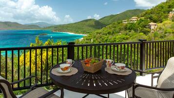Relax in a serene outdoor setting with a tranquil dining experience amidst lush greenery and breathtaking coastal views.