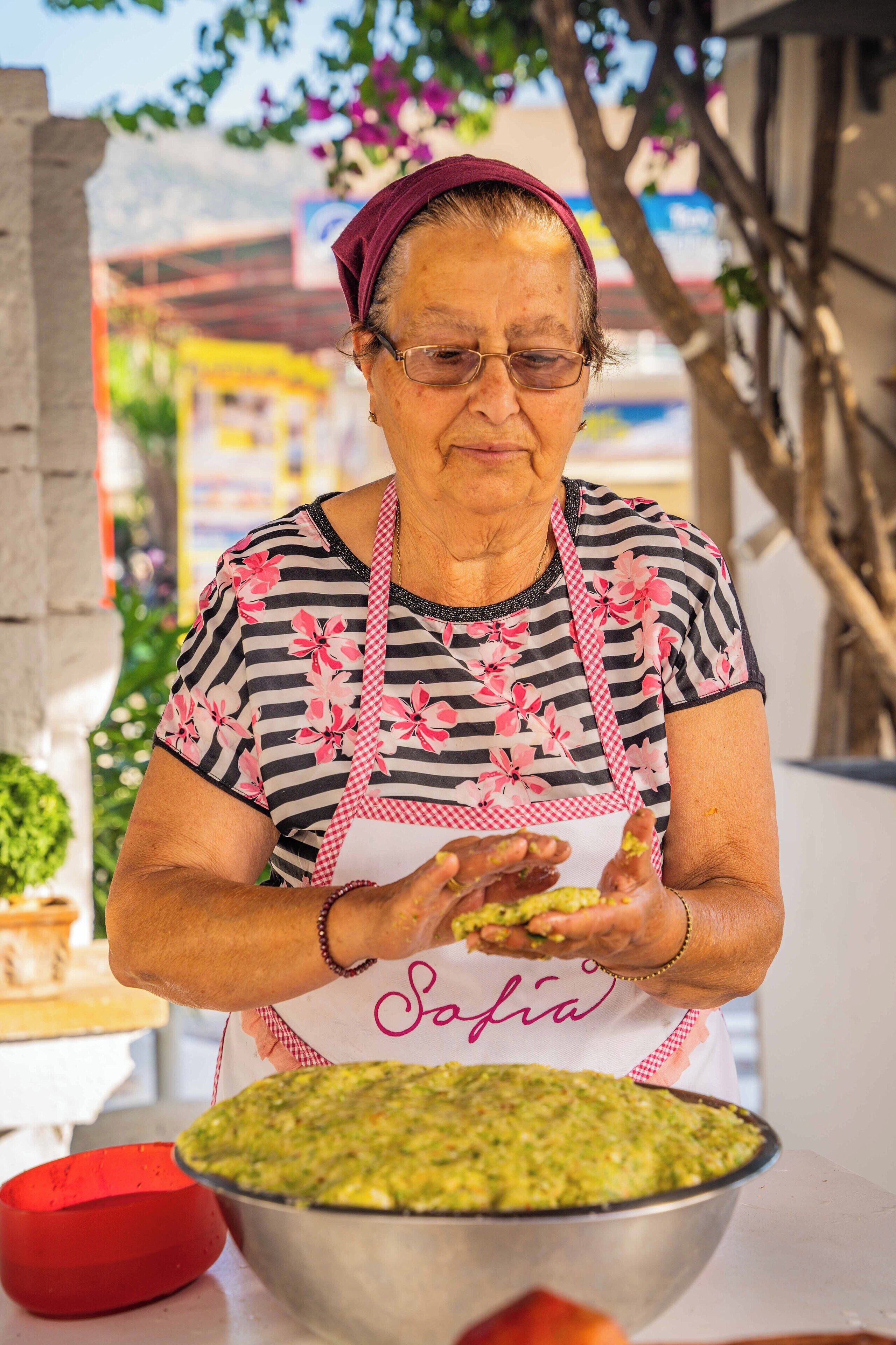 A person wearing a striped shirt and apron, preparing food outdoors.