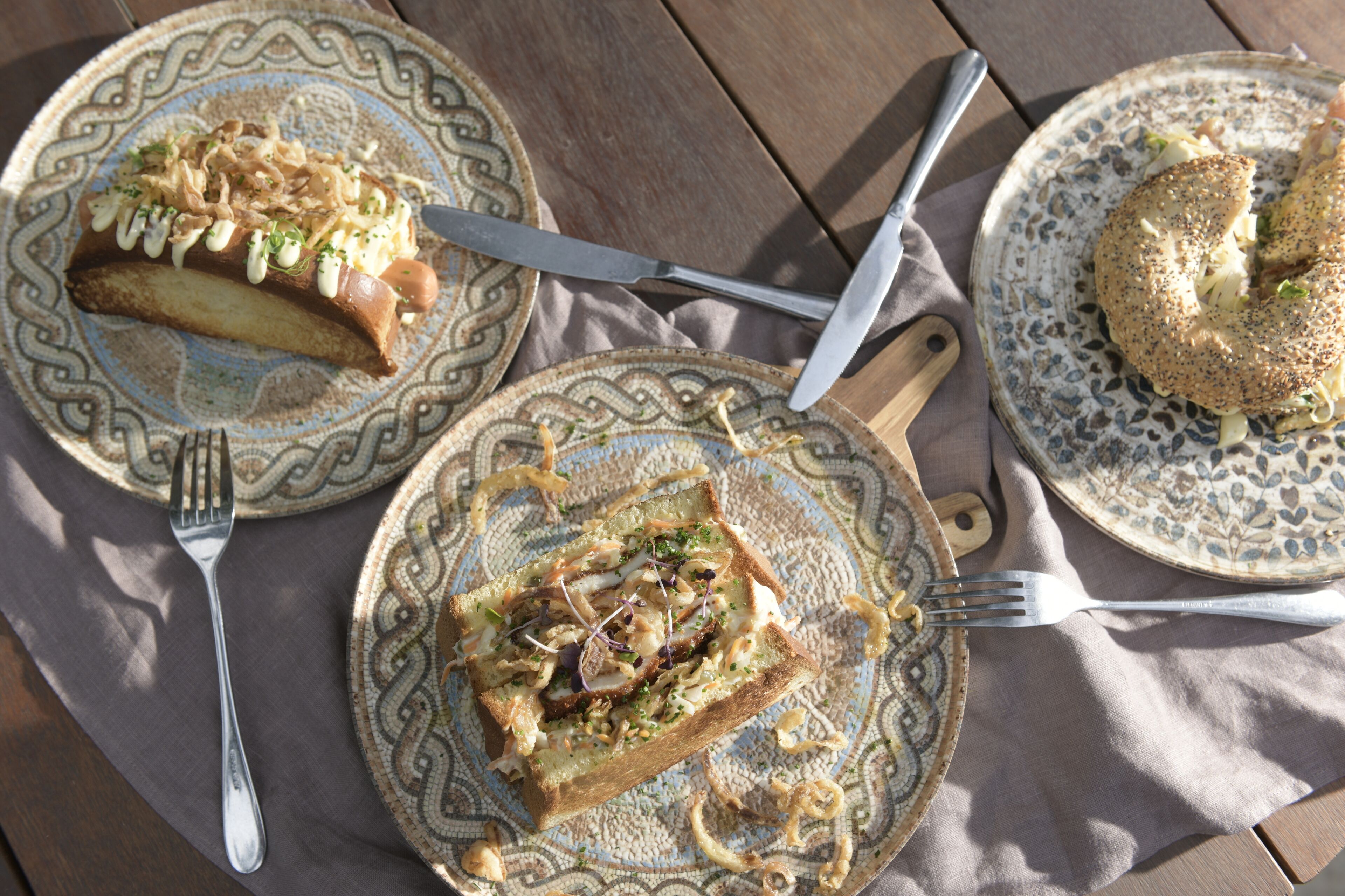 A table with plates of food, utensils, and a napkin.