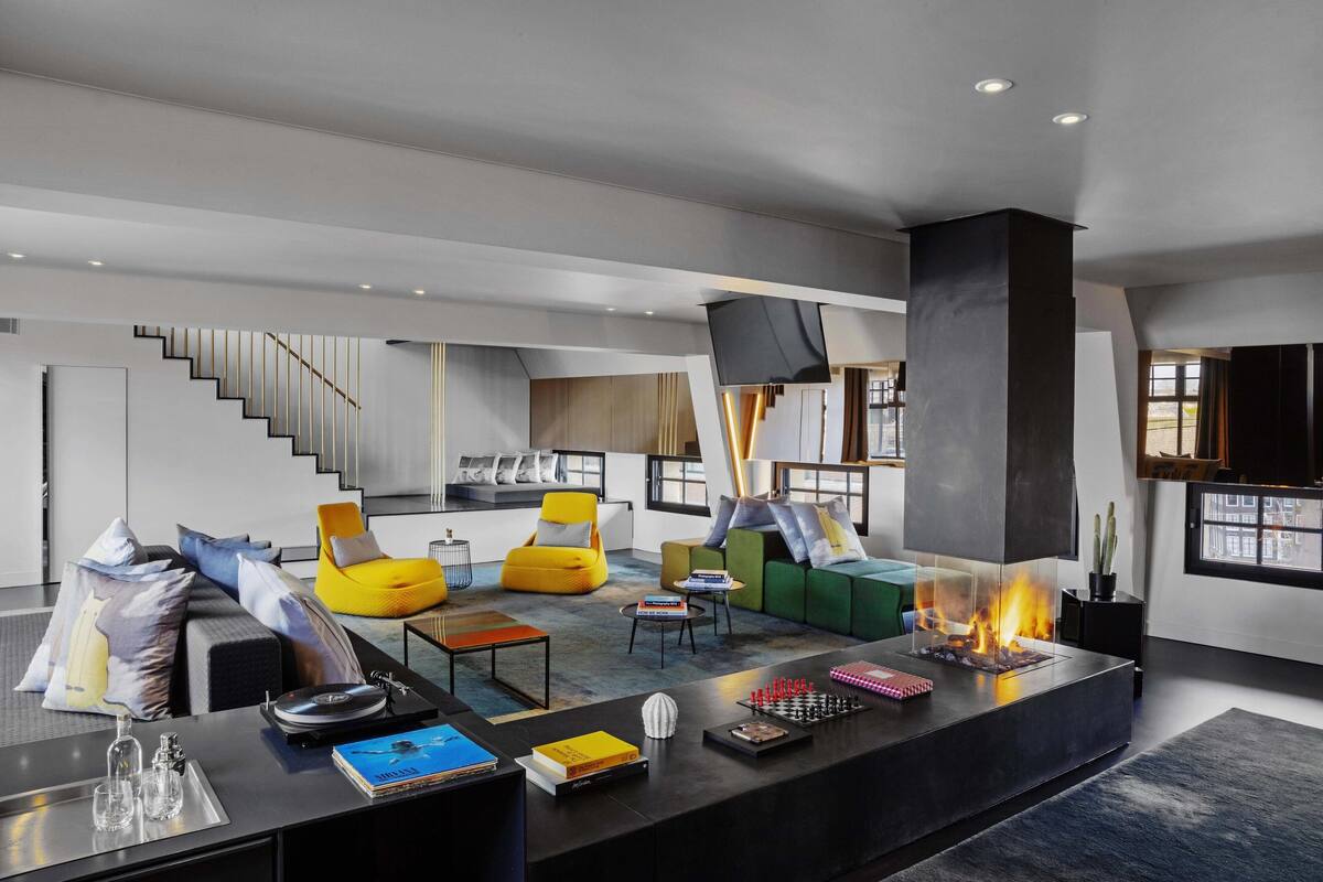 A modern living room with a fireplace, comfortable seating, and a staircase leading to an upper level.