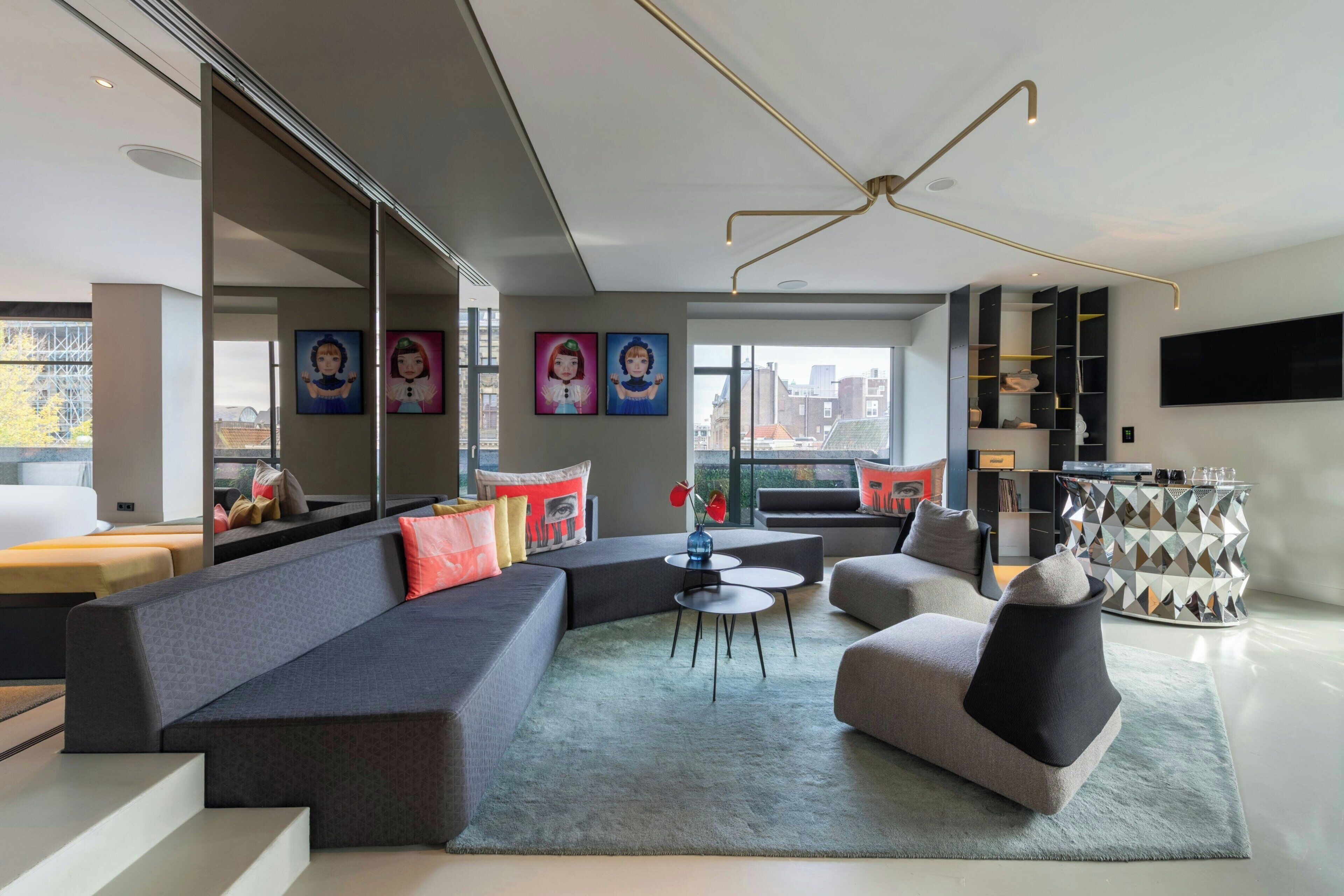 Een moderne woonkamer met een modulaire bank, een ronde salontafel en een flatscreen televisie aan de muur.