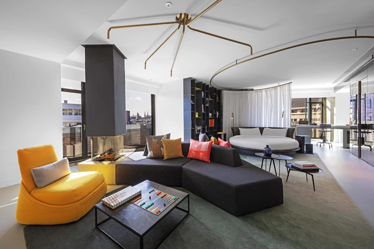 A modern living room with a sectional sofa, a yellow armchair, a coffee table, and a bookshelf.