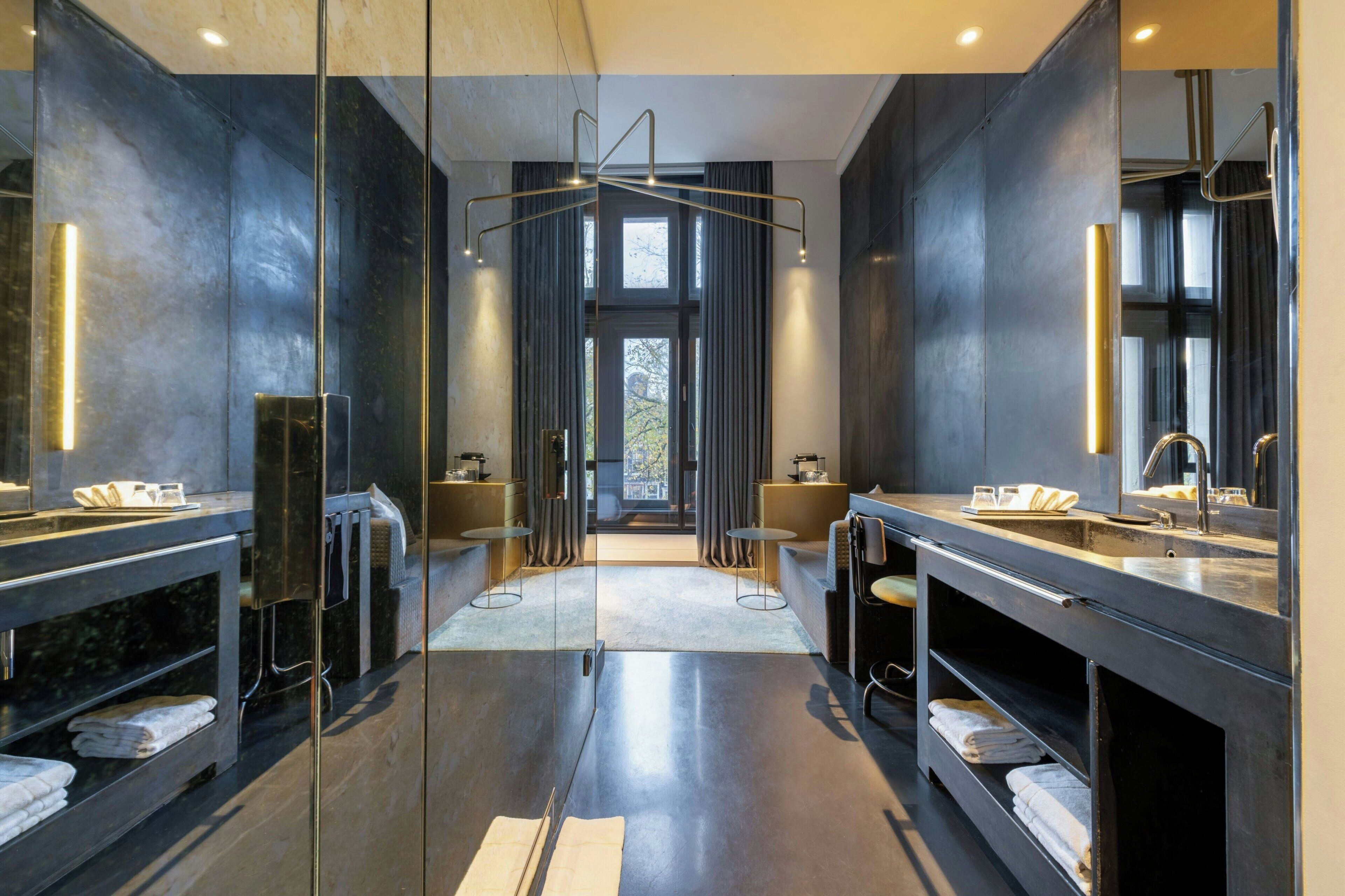 Een moderne badkamer met twee wasbakken, grote spiegels en een centrale verlichtingsarmatuur.