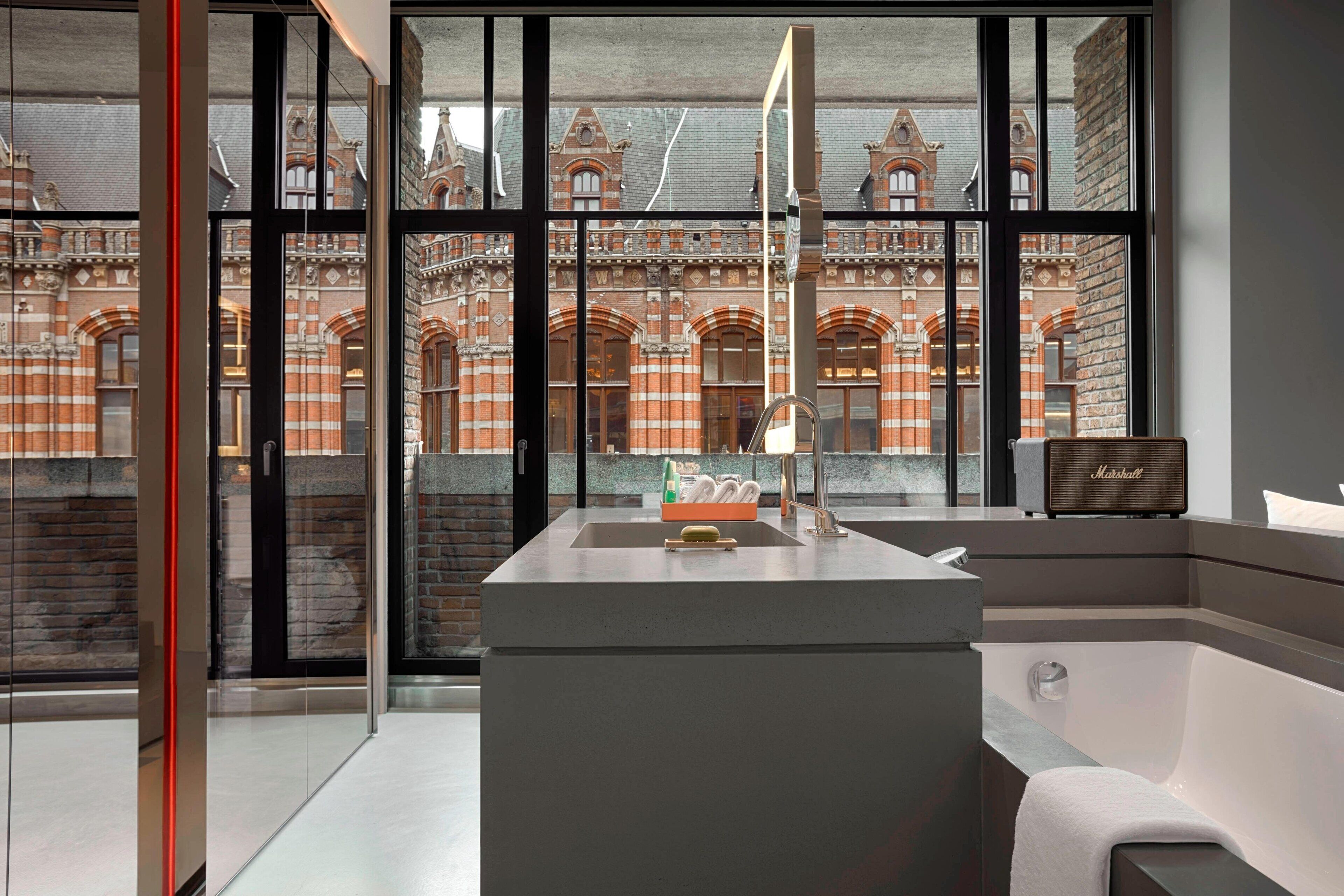 A modern bathroom with a large window, a bathtub, and a marble countertop.