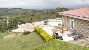 Uma casa com área de pátio, um carro estacionado na frente e vista para as colinas ao redor.