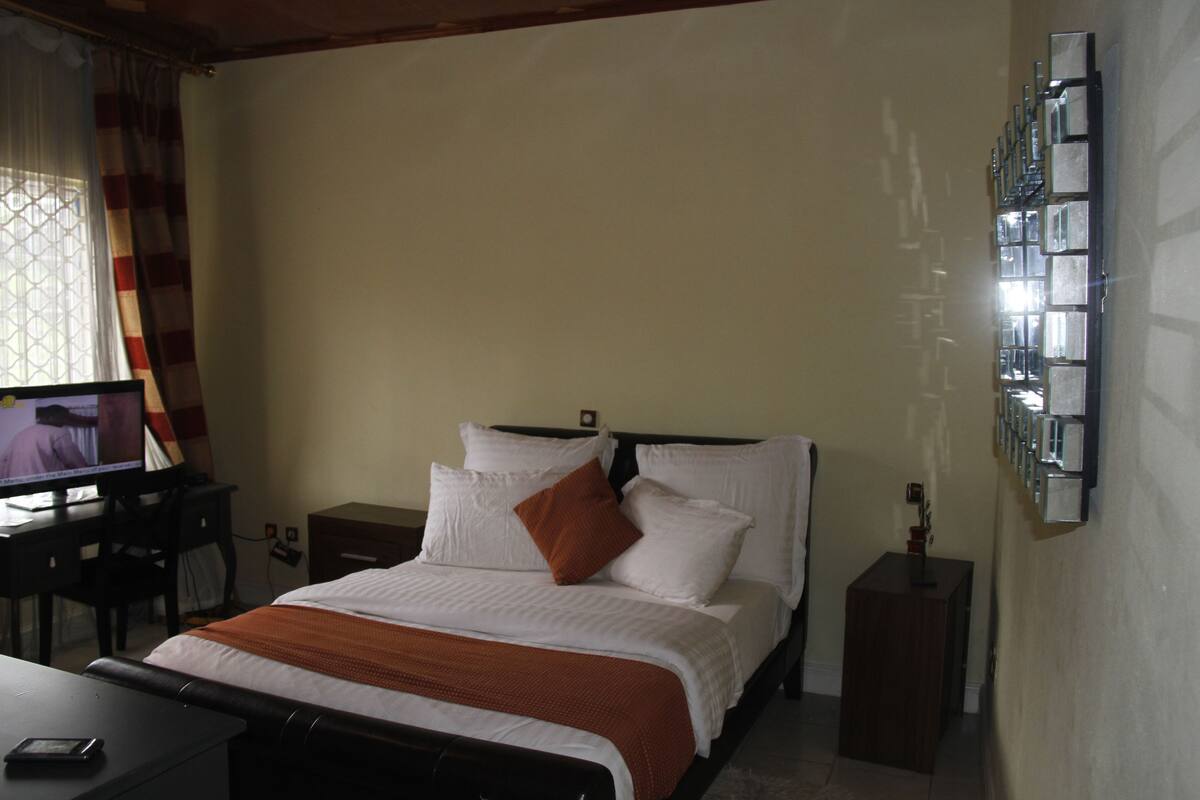 A hotel room with a bed, a desk with a computer, and a TV.