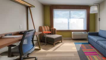 Una habitación con escritorio, silla de oficina, sofá y ventana con vistas.