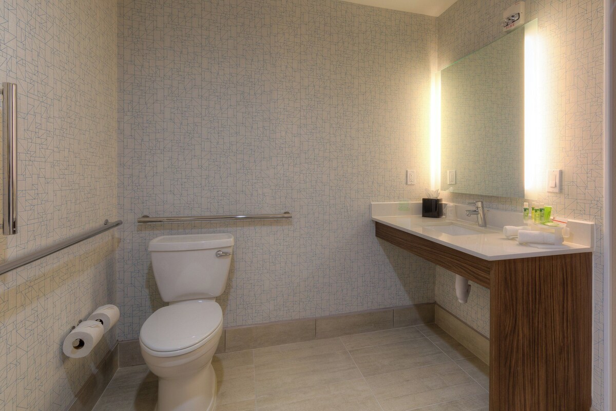 A bathroom with a toilet, a sink, a mirror, and a towel rack.