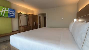 A hotel room with a large bed, a wardrobe, a mirror, and a sign for Holiday Inn Express & Suites.
