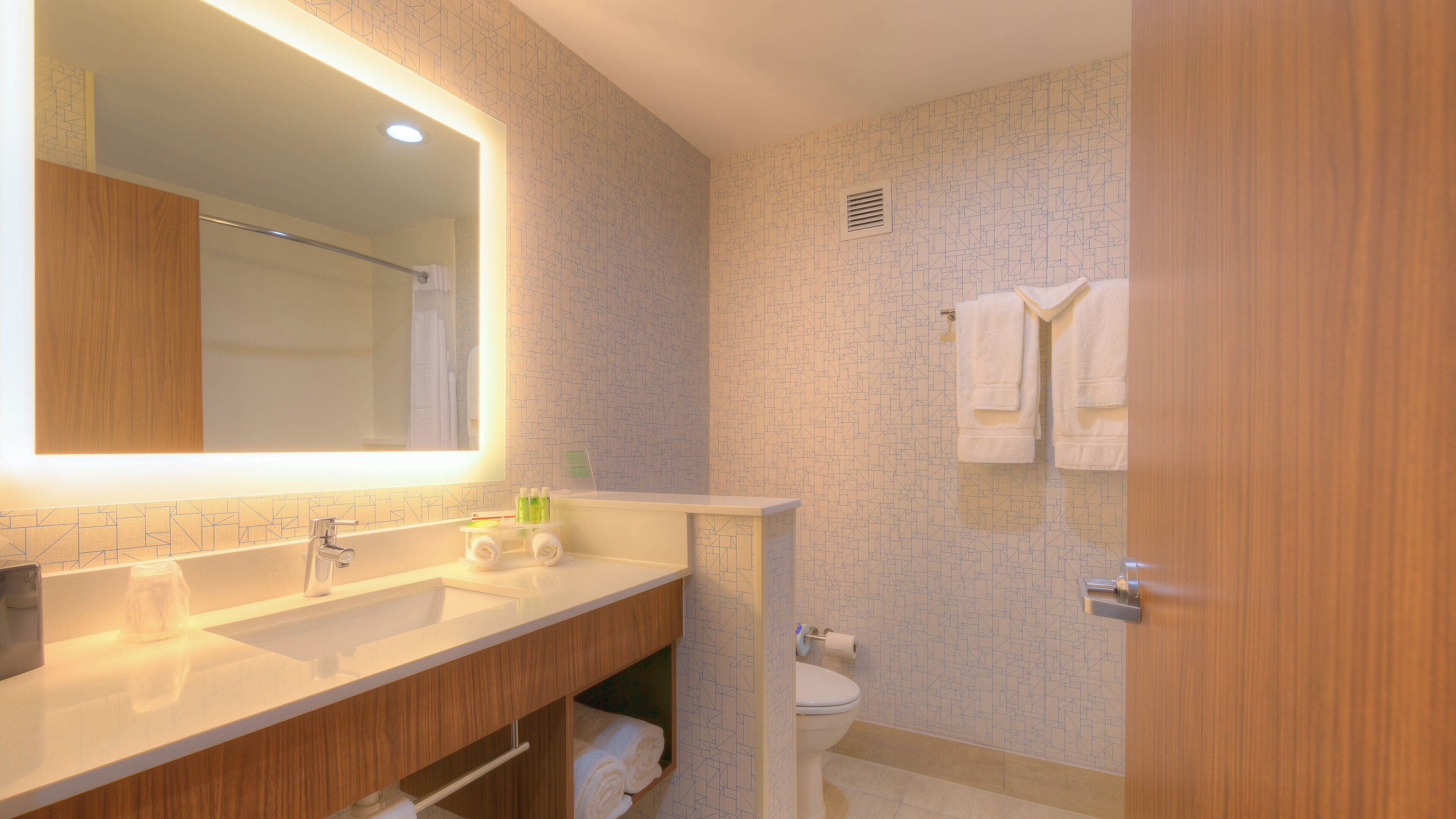 Un baño moderno con un espejo grande, dos lavabos, un inodoro y una zona de ducha.