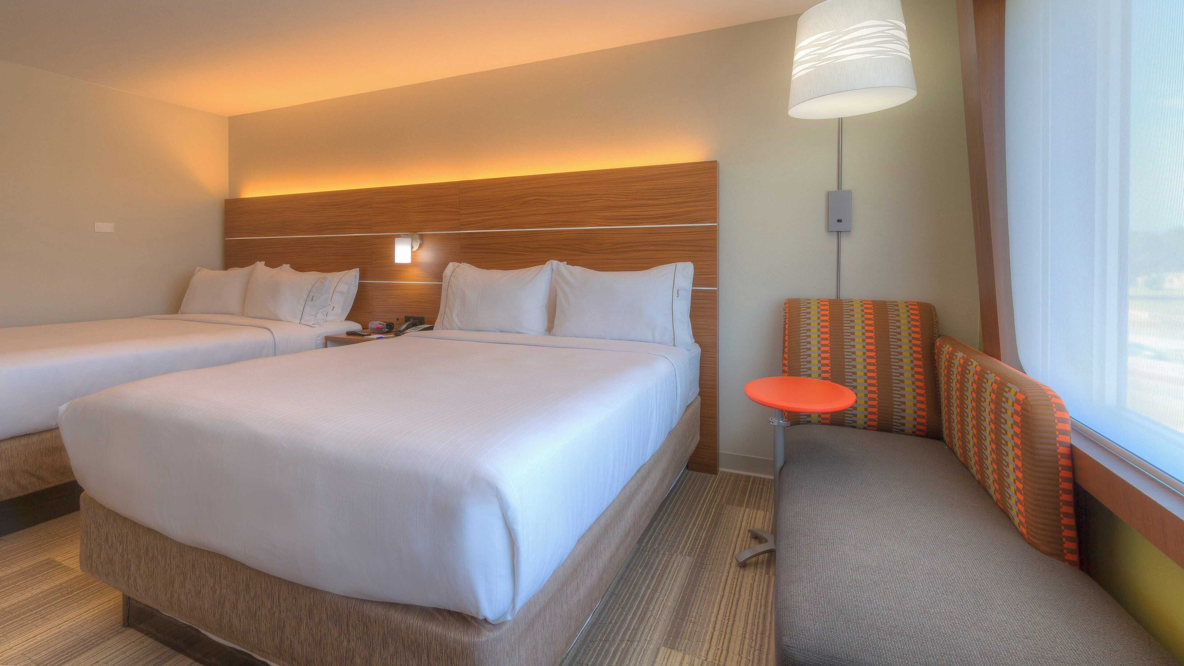 A hotel room with two beds, a small table, and a sofa.