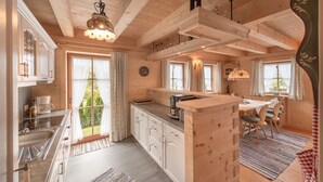A wooden cabin interior with a kitchen, dining area, and large windows. - Ötztal Chalet (Sautens)